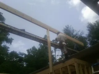 Carpenter setting a ridge beam over a new addition frame — Ice Dam Removal by Roofing Brothers in Lincolndale