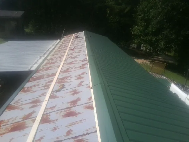 Old rusted panels beside newly installed green metal roofing — Wind Damage Roof Repair by Roofing Brothers in Lincolndale