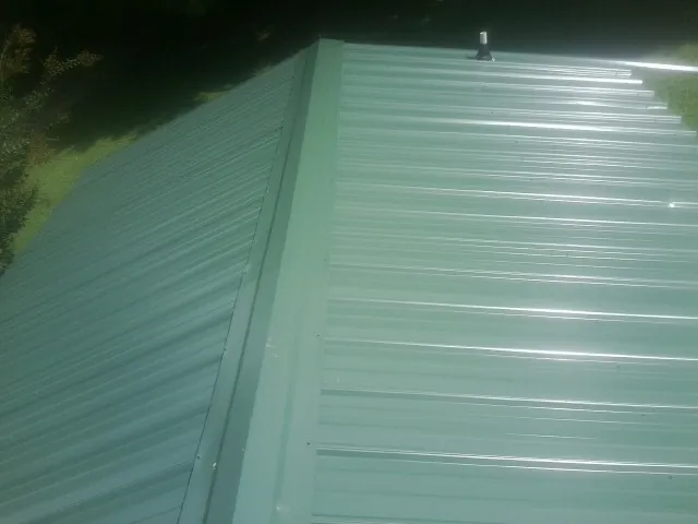 New green metal panels meeting at the ridge of a roof — Flat Roof Repair work by our crew in Lincolndale