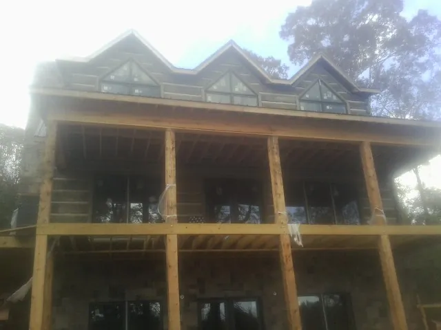 Dormers and porch framing on a large log home under construction — Roof Coating work by our crew in Lincolndale