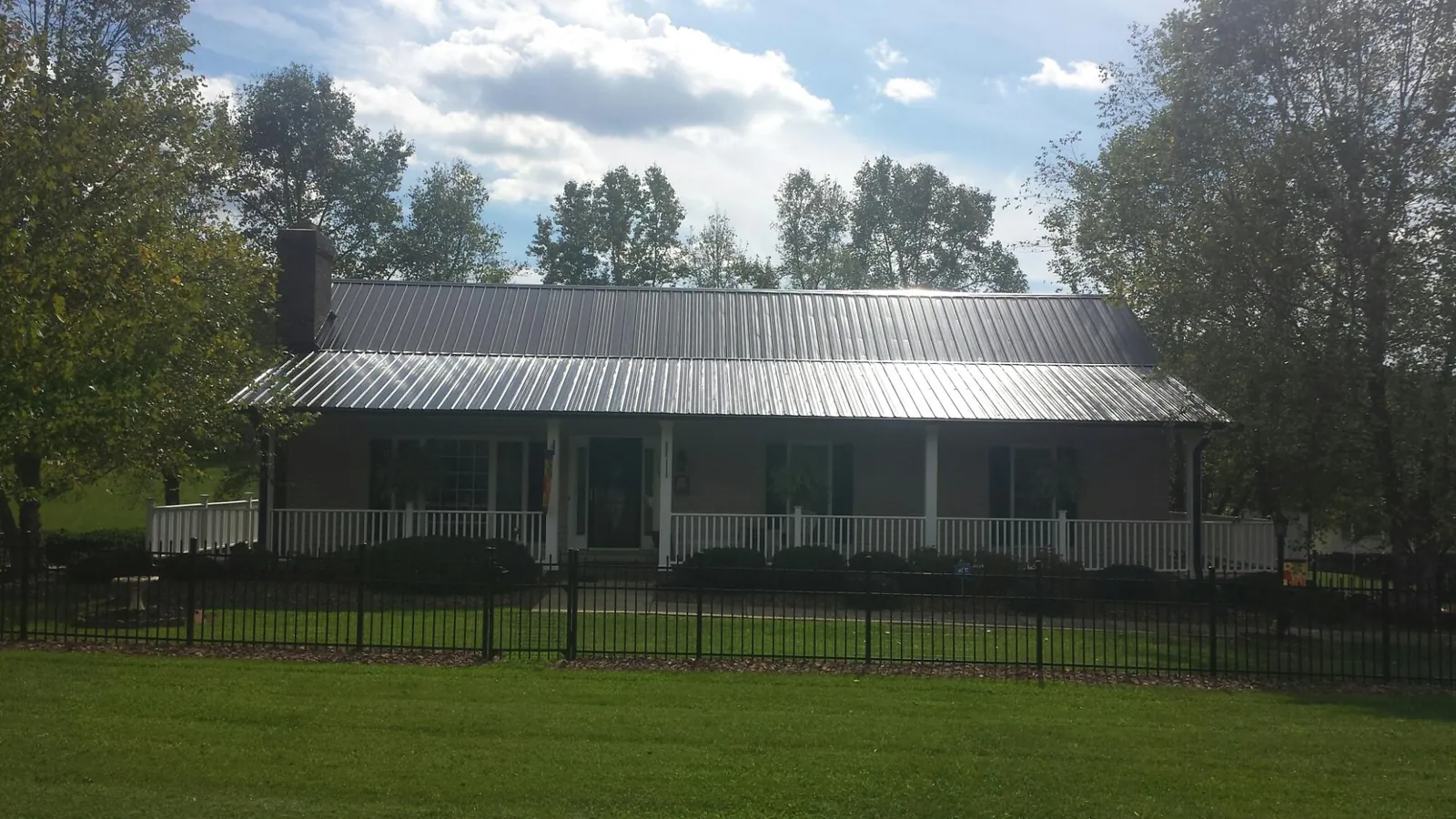 Gray metal roof on a brick ranch with a full width front porch — Gutter Guard Installation work by our crew in Lincolndale
