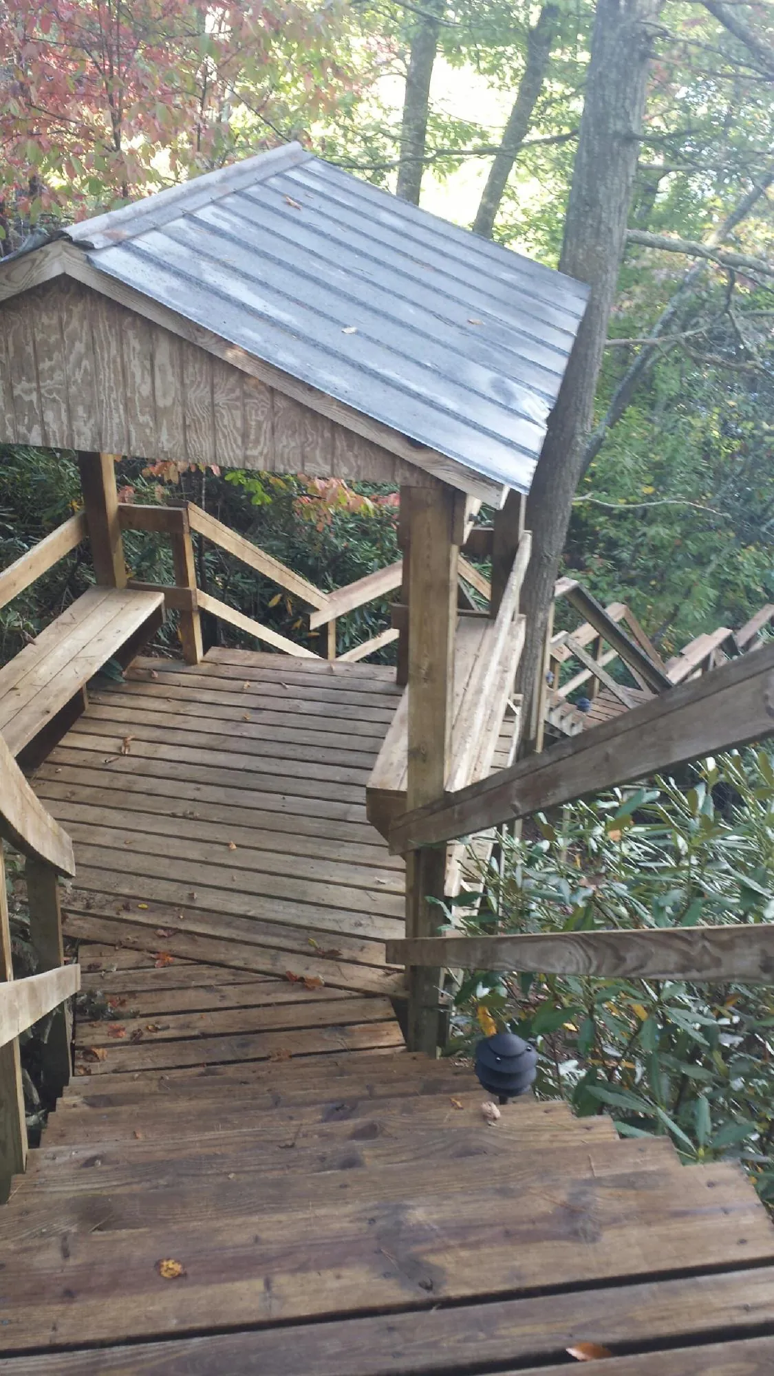 Metal roofed shelter over wooden steps on a wooded walkway — Skylight Repair & Installation work by our crew in Lincolndale