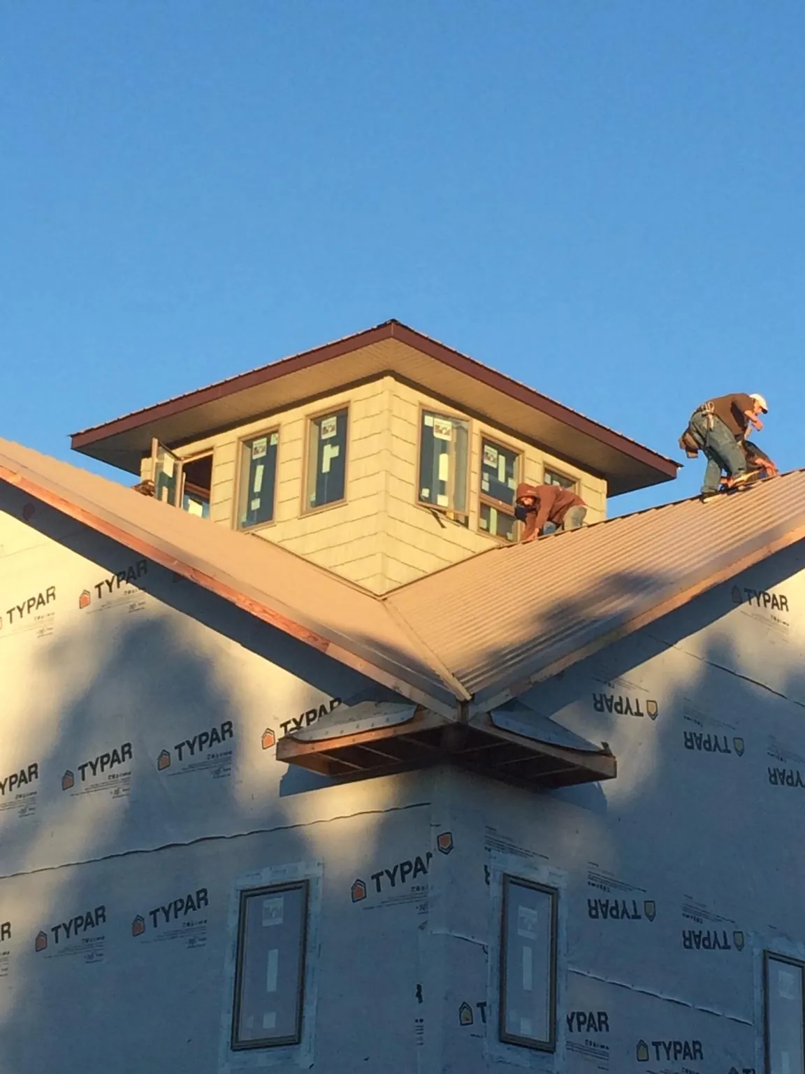 Roofers working around a rooftop cupola on a new metal roof at sunset — Roof Waterproofing in Lincolndale by Roofing Brothers